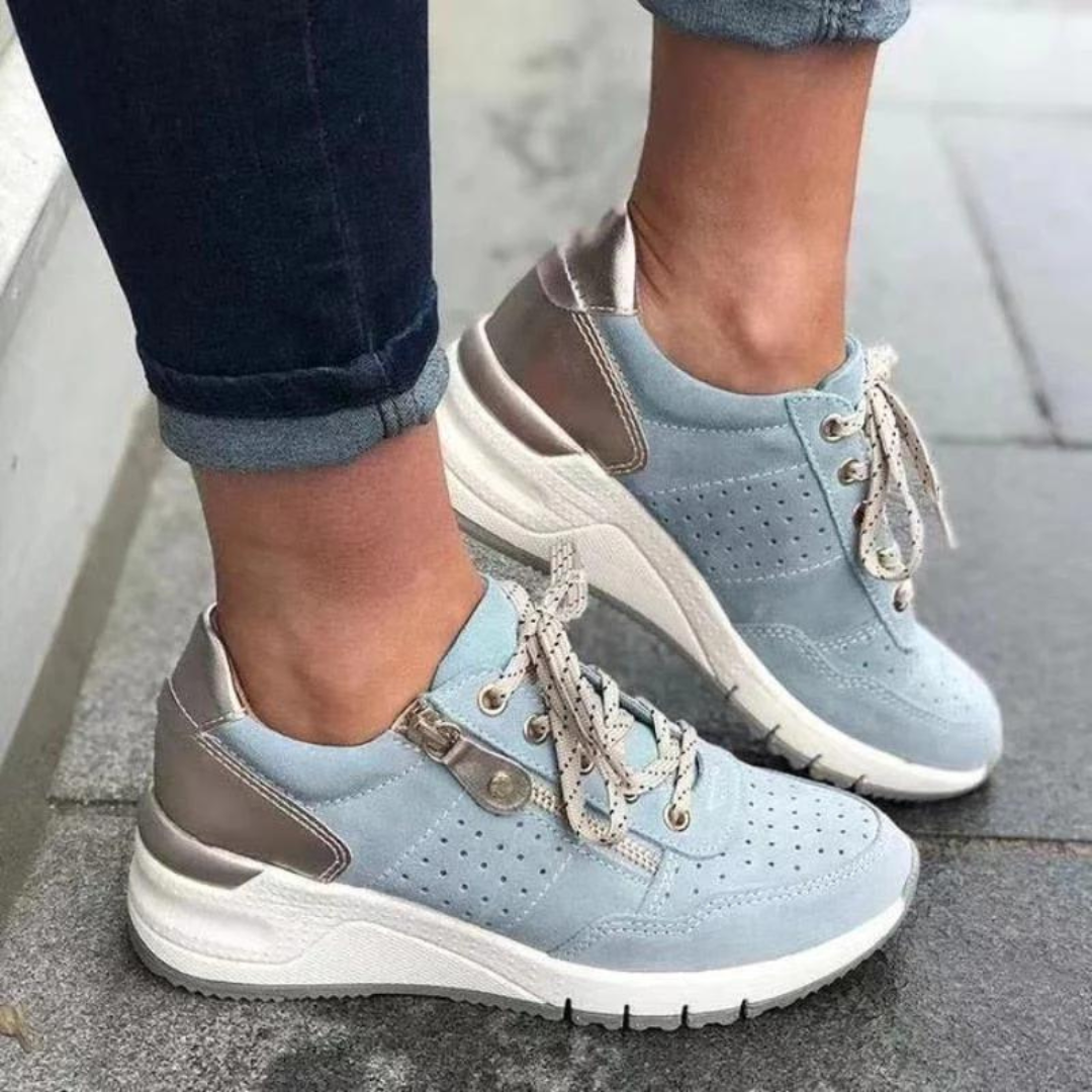 Damen Sneaker in Hellblau mit weißen Sohlen und silbernen Details, getragen auf grauem Pflaster. Modische Freizeitschuhe, bequem und stilvoll.