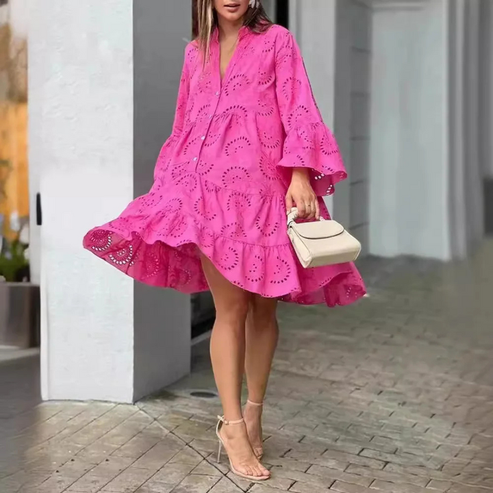Frau in pinkem Spitzenkleid mit Rüschen, hält weiße Handtasche, trägt Sandalen. Modetrend, Sommerkleid, eleganter Look, Stadtbummel.