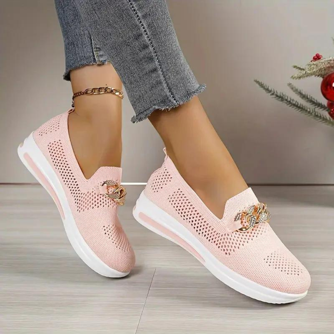 Damen rosa Sneaker mit Strassverzierung, atmungsaktivem Mesh-Obermaterial und weißer Sohle, getragen mit grauer Jeans. Modische Freizeitschuhe.