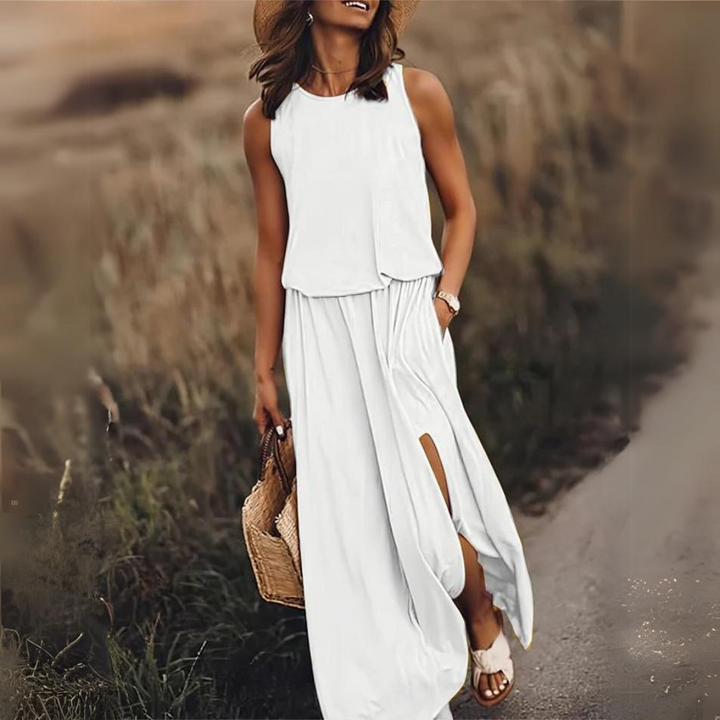 Frau in weißem Sommerkleid mit Strohhut und Korbtasche spaziert auf einem ländlichen Weg. Elegante Mode, Sommeroutfit, Freizeitkleidung.