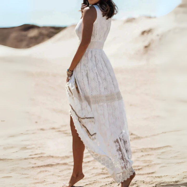 Frau in weißem Spitzenkleid geht barfuß durch Wüste. Sommermode, elegantes Kleid, Boho-Stil, sandige Landschaft, modische Kleidung.