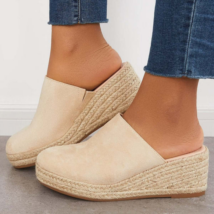 Beige Damen-Pantoletten mit Keilabsatz und Bastsohle, kombiniert mit blauen Jeans. Ideal für Sommermode und lässige Outfits.