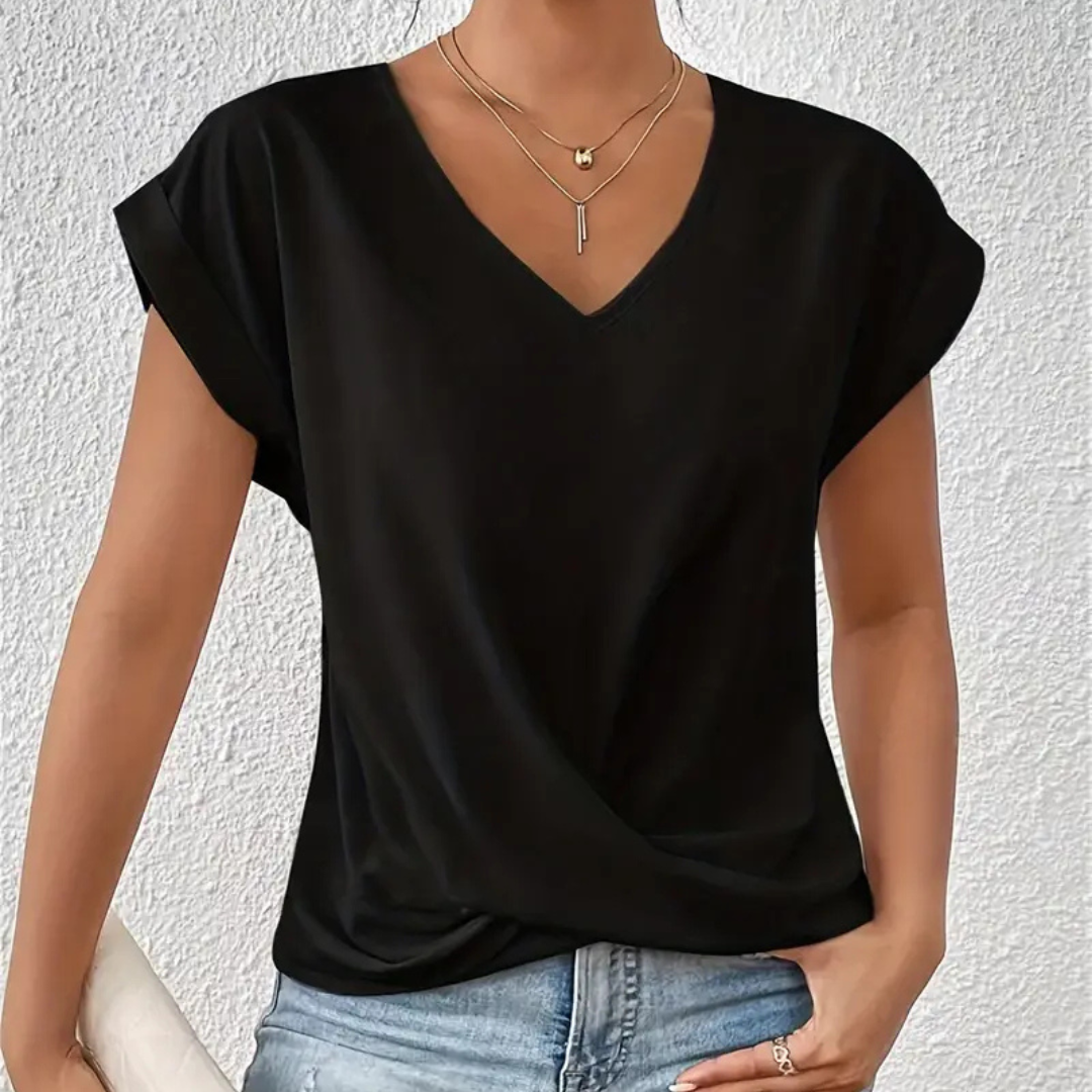 Frau trägt schwarzes V-Ausschnitt-T-Shirt, kombiniert mit blauen Jeans und goldenen Halsketten. Modetrend, lässiger Stil, Damenbekleidung.