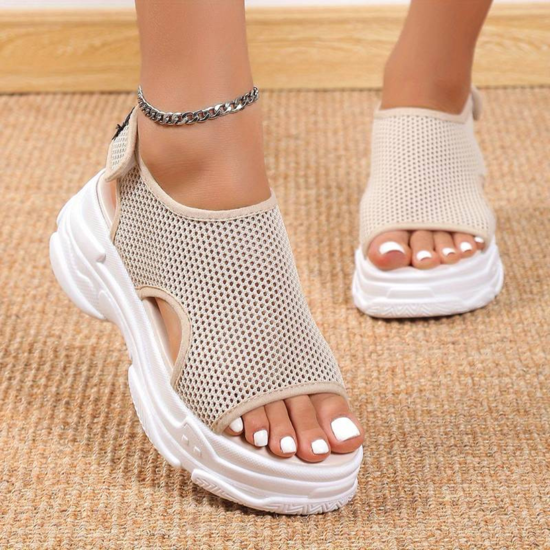Beige Damen-Sneaker-Sandalen mit Mesh-Obermaterial und dicker weißer Sohle auf Teppichboden. Modische Sommerschuhe, bequem und atmungsaktiv.