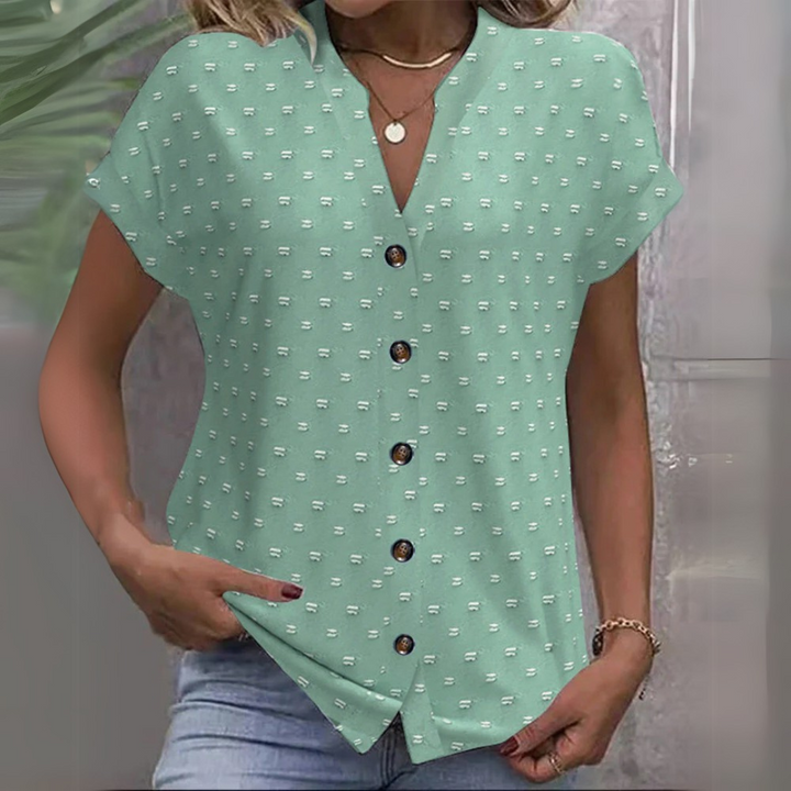Frau trägt mintgrüne Bluse mit Knopfleiste und Muster, kombiniert mit blauer Jeans. Modetrend, Sommeroutfit, Damenbekleidung.