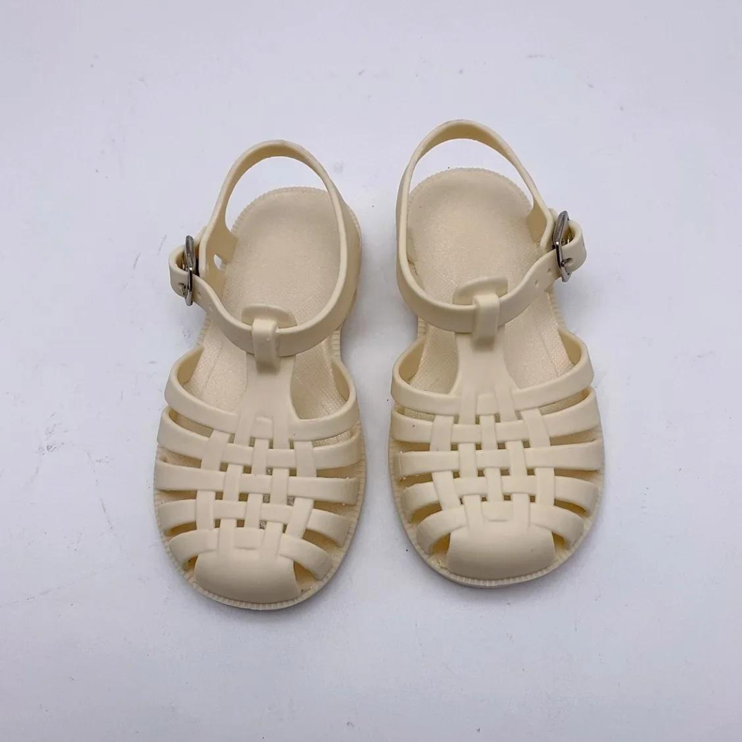 Beige Kinder-Sandalen aus Kunststoff mit Riemen und Schnalle, ideal für Sommer und Strand. Robustes Design, bequem und modisch für Kinder.