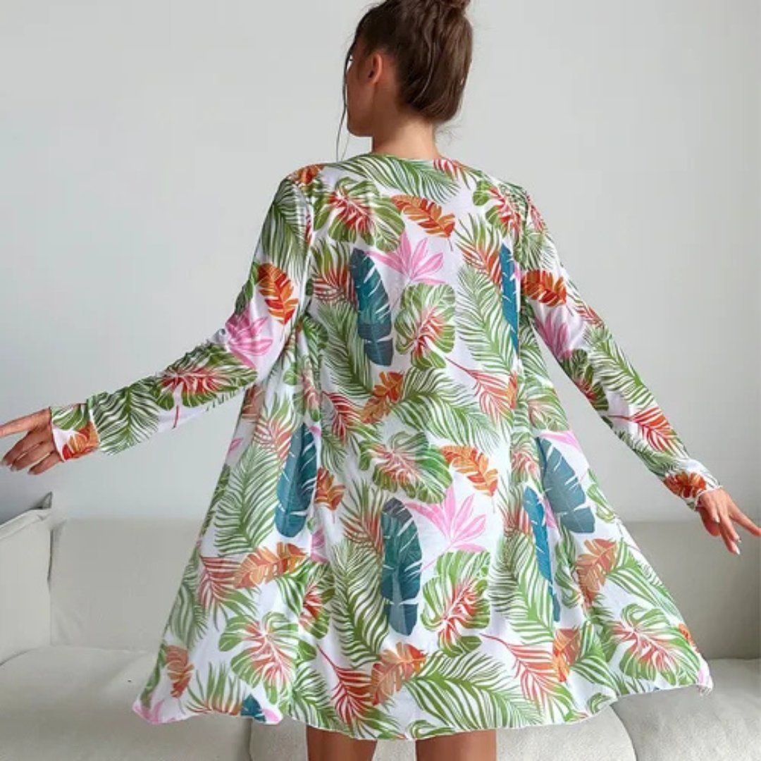 Rückansicht einer Frau in einem bunten, geblümten Kleid mit tropischem Muster, das im Wohnzimmer schwingt. Modetrend, tropisches Design, Damenmode.