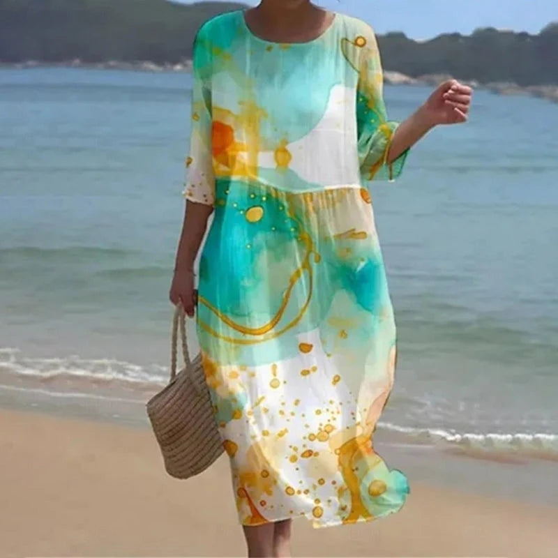 Frau in langem, farbenfrohem Sommerkleid am Strand, trägt Strohtasche. Perfekt für Strandmode, Sommerkleider, Freizeitkleidung.