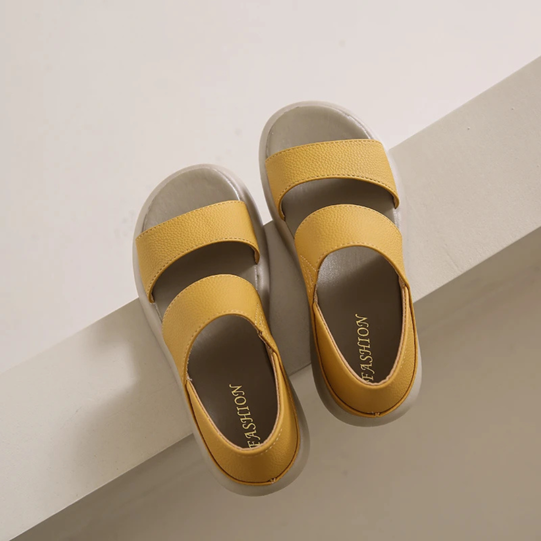 Gelbe Sandalen mit zwei Riemen auf hellem Hintergrund, modisches Design, bequeme Sommerschuhe, ideal für Damen, trendige Fußbekleidung.