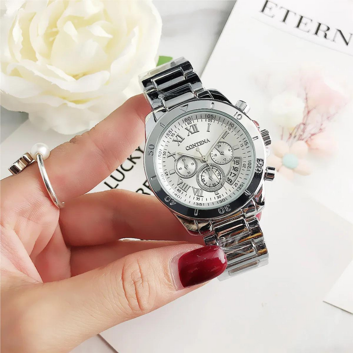 Silberne Damenarmbanduhr mit Chronographen-Zifferblatt, gehalten von Hand mit rotem Nagellack, weiße Rose im Hintergrund. Elegante Uhr für Frauen.
