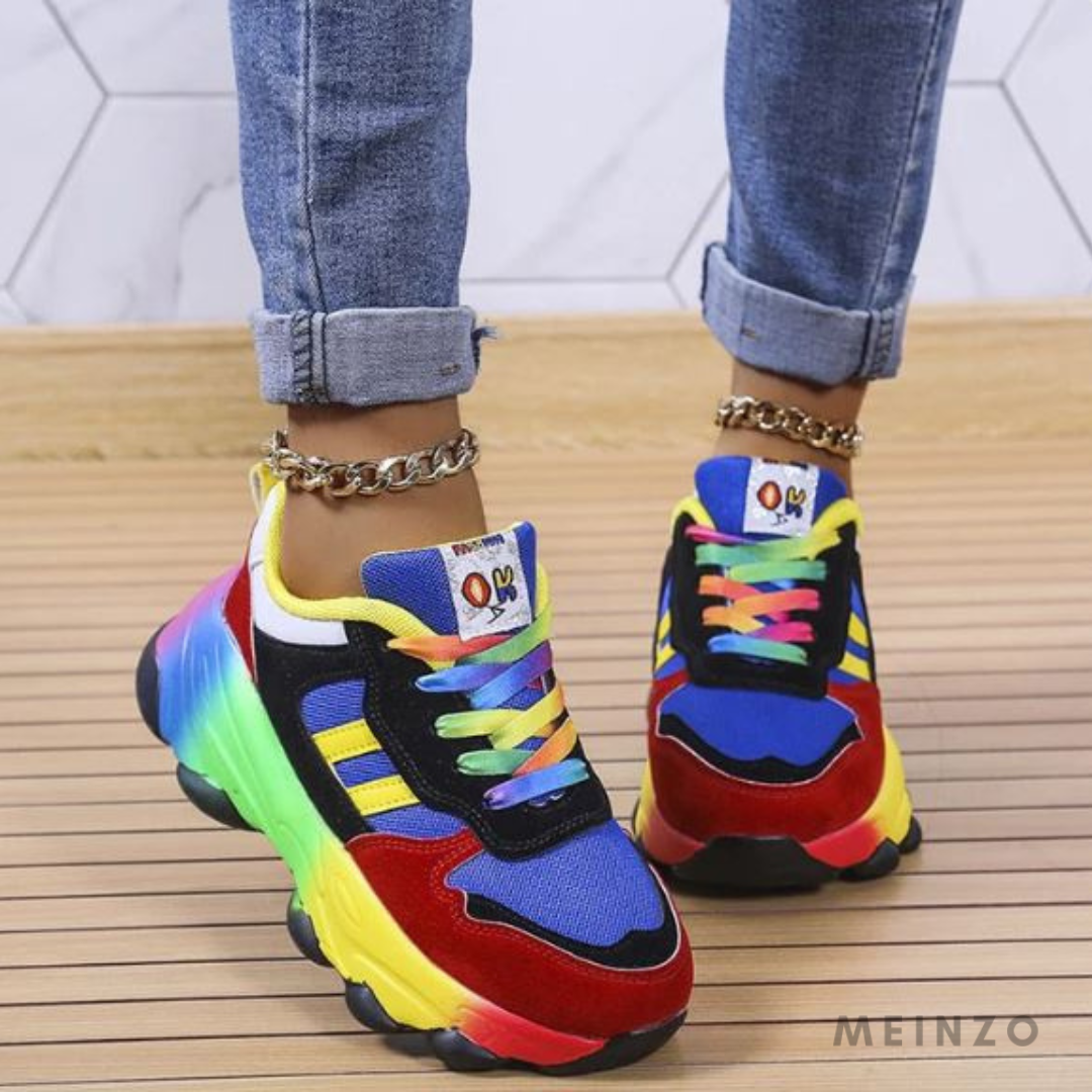 Bunte Sneaker mit Regenbogenfarben, getragen von Person in Jeans. Modische Sportschuhe, auffälliges Design, trendige Damenmode, urbaner Stil.