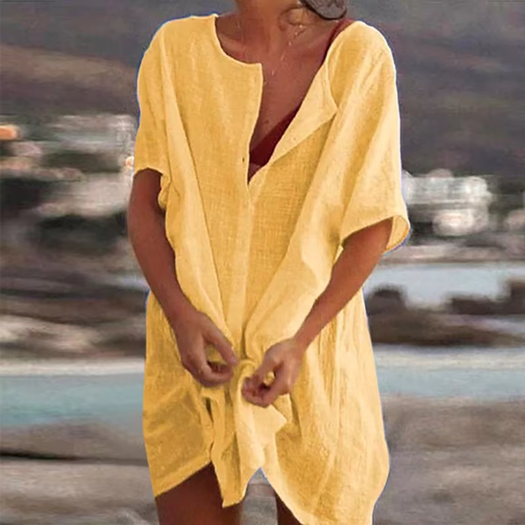 Frau in gelbem Leinenkleid am Strand, sommerliche Mode, lässiger Stil, Urlaubskleidung, entspannte Atmosphäre, Strandhintergrund.