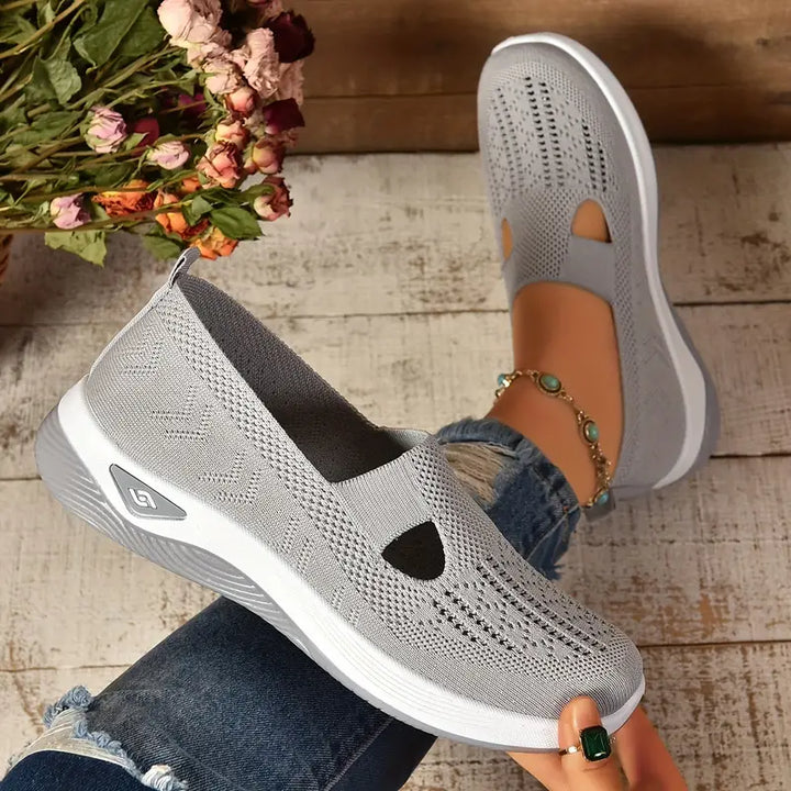 Graue Damen-Sneaker aus atmungsaktivem Strickmaterial, getragen von Person mit Jeans. Bequeme Freizeitschuhe, ideal für den Alltag.