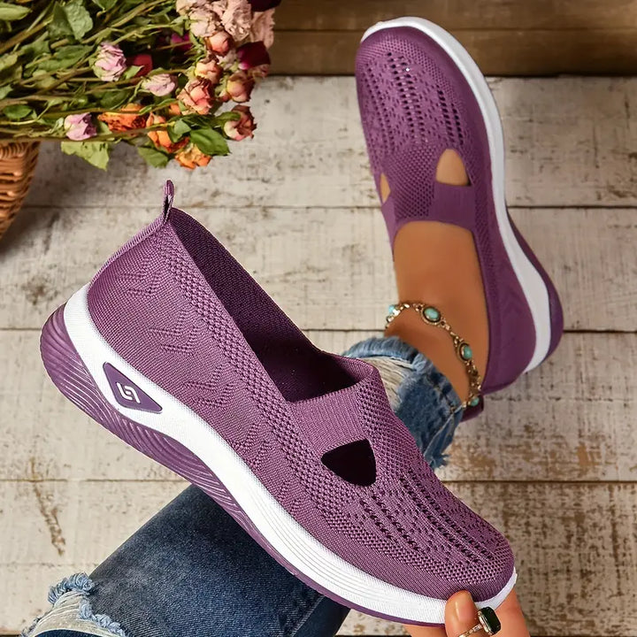 Lila Damen-Sneaker mit Strickmuster, atmungsaktivem Design und weißer Sohle, getragen von Person auf Holzfußboden, modisch und bequem.