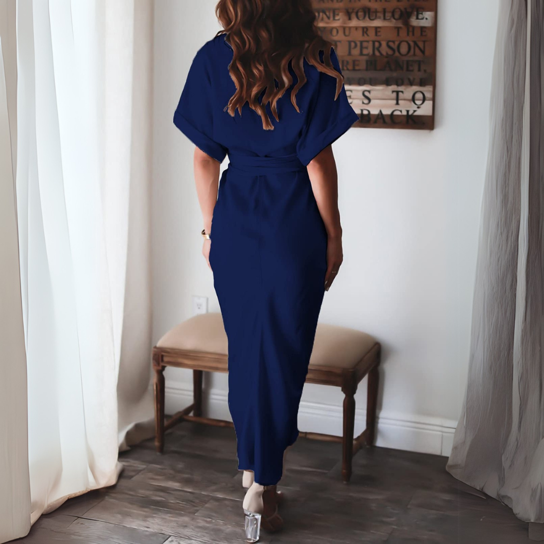 Frau in elegantem, blauem Kleid von hinten, steht in modernem Wohnzimmer mit Holzboden und Vorhängen. Stilvolle Mode, Inneneinrichtung, Damenbekleidung.