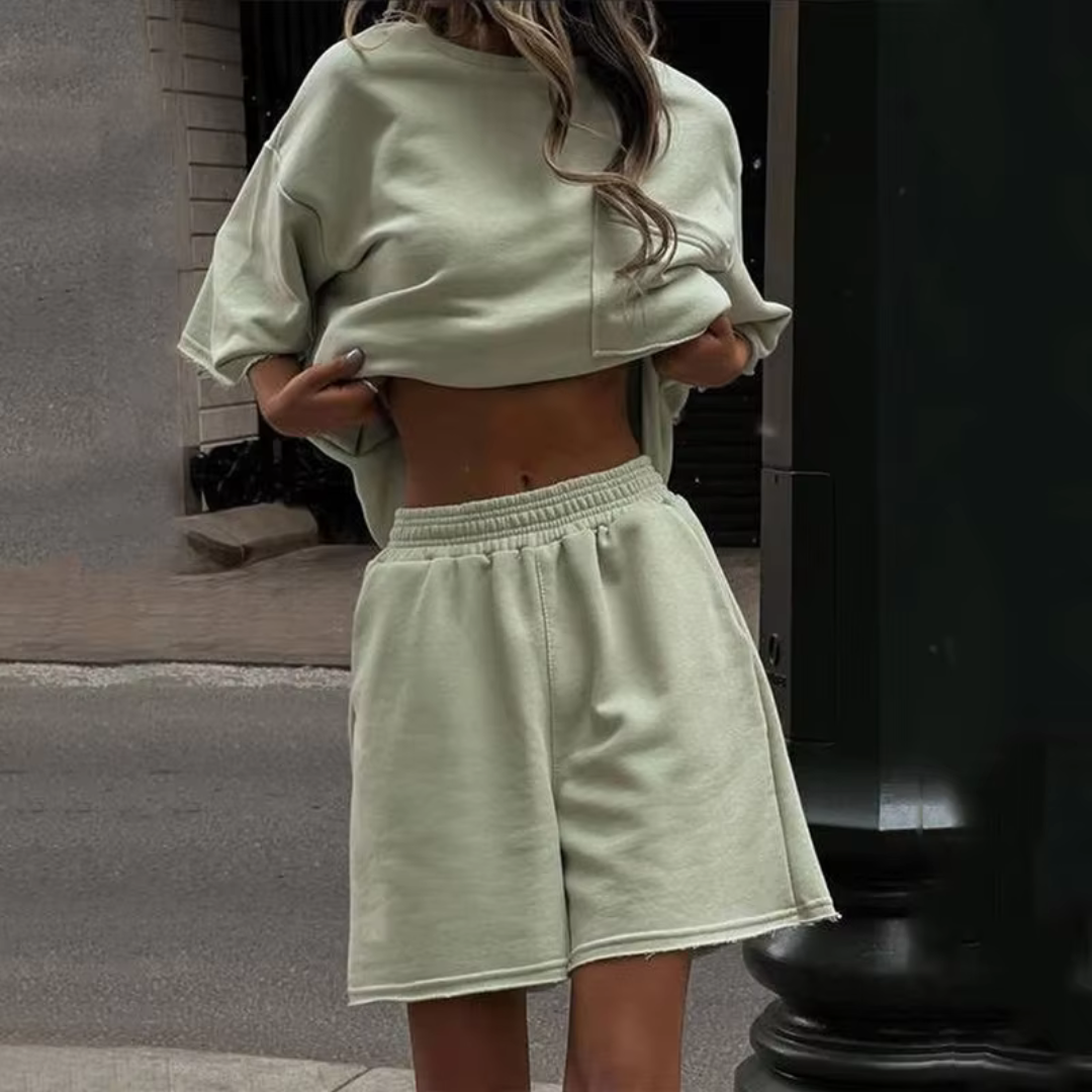 Dame in mintgrünem Oversize-Sweatshirt und Shorts auf Straße. Modetrend, lässiger Stil, urbaner Look, Sommeroutfit, Streetwear.