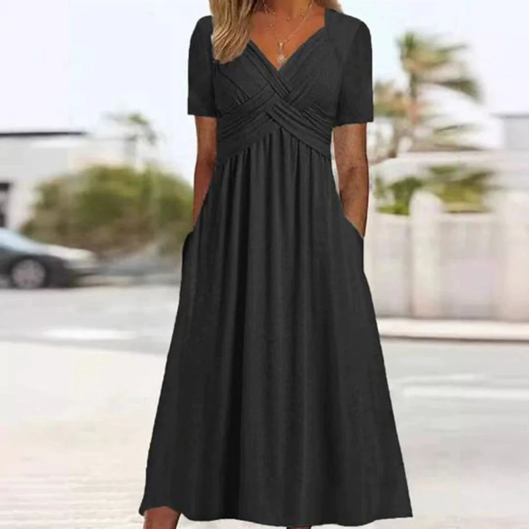 Frau in elegantem, schwarzem Maxikleid mit kurzen Ärmeln und V-Ausschnitt, steht draußen. Perfekt für Sommermode und Freizeitkleidung.