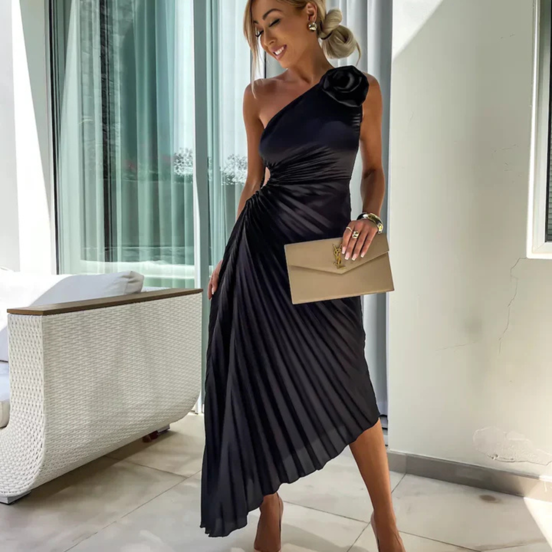 Eine Frau in einem eleganten, schwarzen, schulterfreien Abendkleid mit Plissee-Design, hält eine beige Clutch. Perfekt für formelle Anlässe.