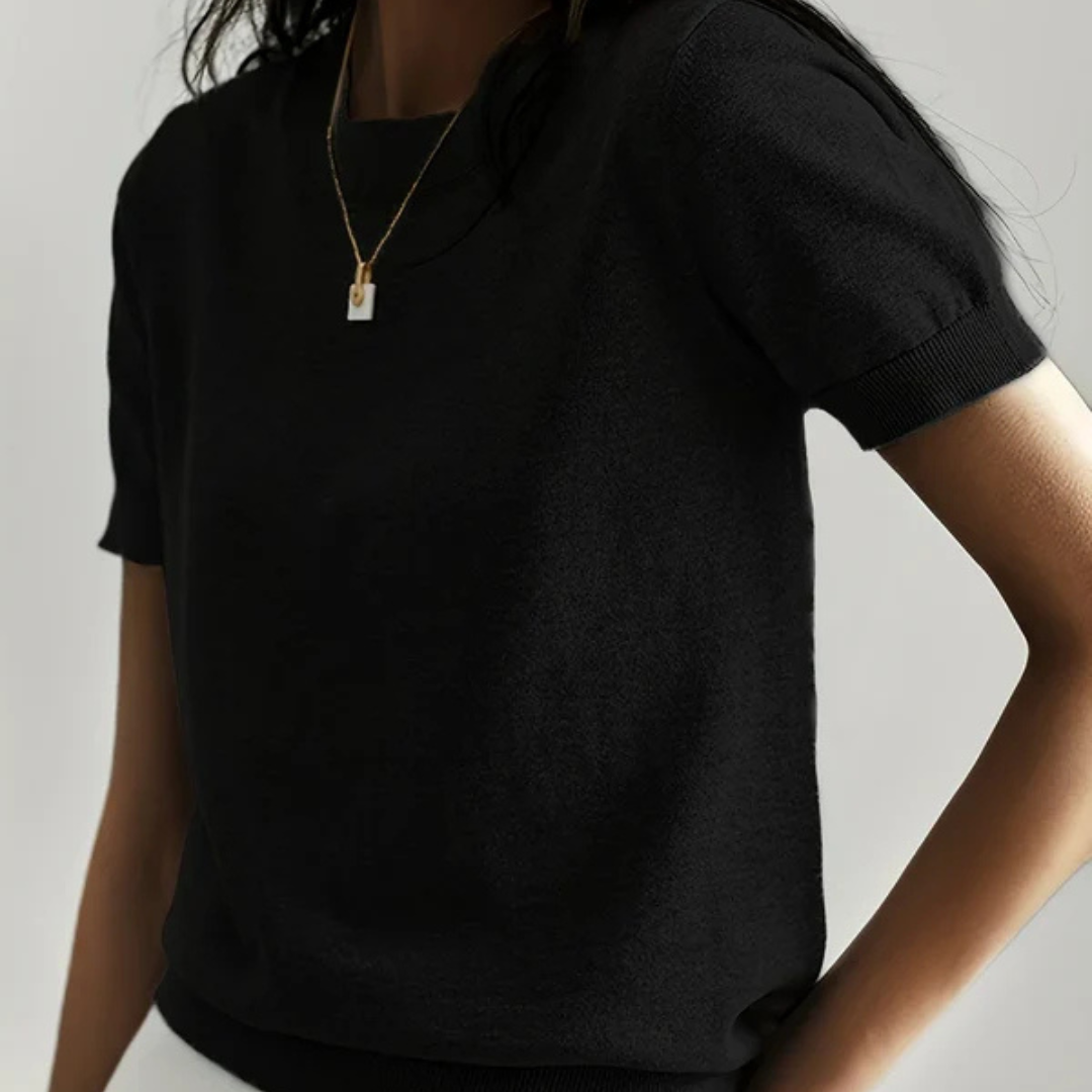 Frau in schwarzem T-Shirt mit kurzem Ärmel und goldener Halskette, minimalistisch, Mode, eleganter Stil, modernes Design, neutraler Hintergrund.