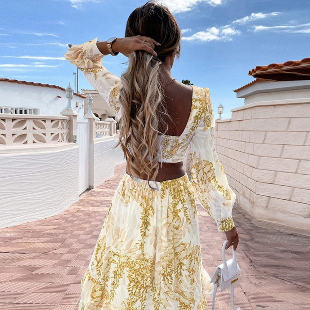 Frau in geblümtem Sommerkleid auf sonniger Terrasse, blonde Haare, Rückenansicht, blauer Himmel, modisch, elegant, Urlaubsstimmung, stilvoll.