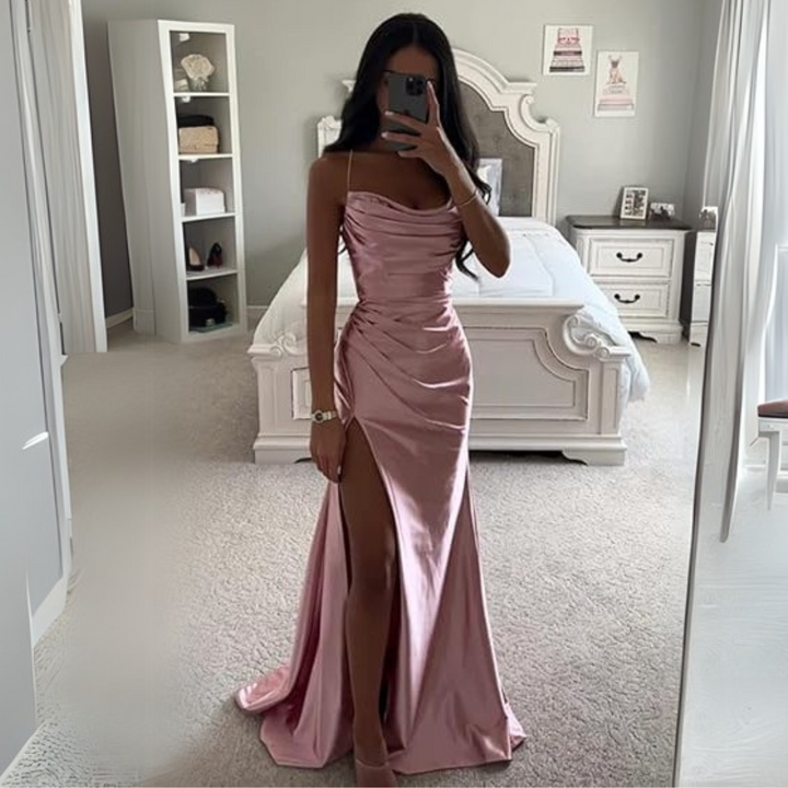 Frau in rosa Abendkleid mit hohem Schlitz, steht vor einem Spiegel in einem eleganten Schlafzimmer. Luxuriöse Mode, Abendgarderobe, stilvolles Design.