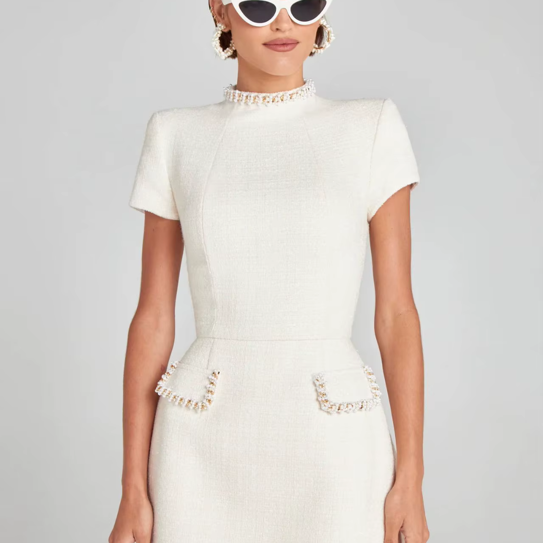 Weiße, elegante Damenkleid mit kurzen Ärmeln und Taschen, getragen von Frau mit Sonnenbrille. Perfekt für stilvolle Anlässe und Modeevents.