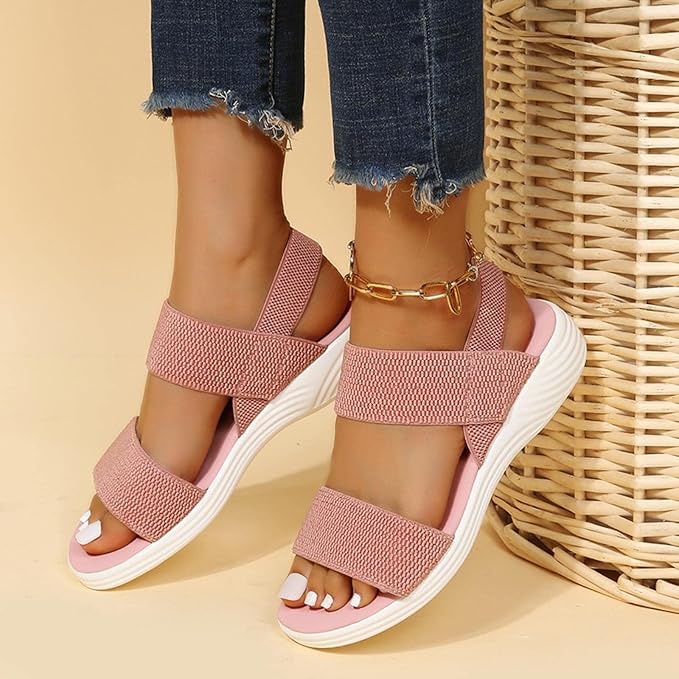 Damen Sandalen in Rosa mit elastischen Riemen und weißer Sohle, getragen mit Jeans. Modische Sommerschuhe, bequem und stilvoll.