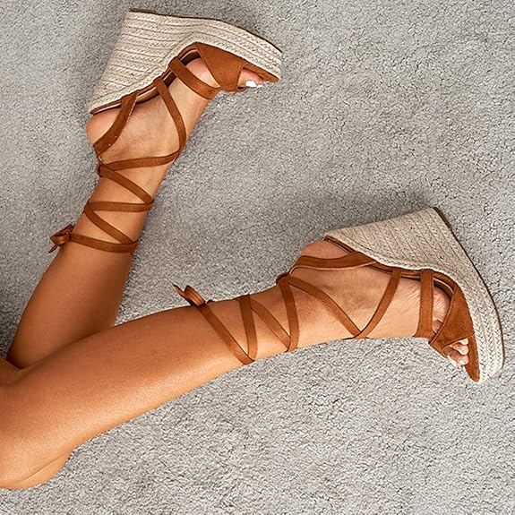Braune Keilsandalen mit Riemchen auf beigem Teppich. Modische Sommerschuhe, Damenmode, bequeme Absatzsandalen, trendige Fußbekleidung.