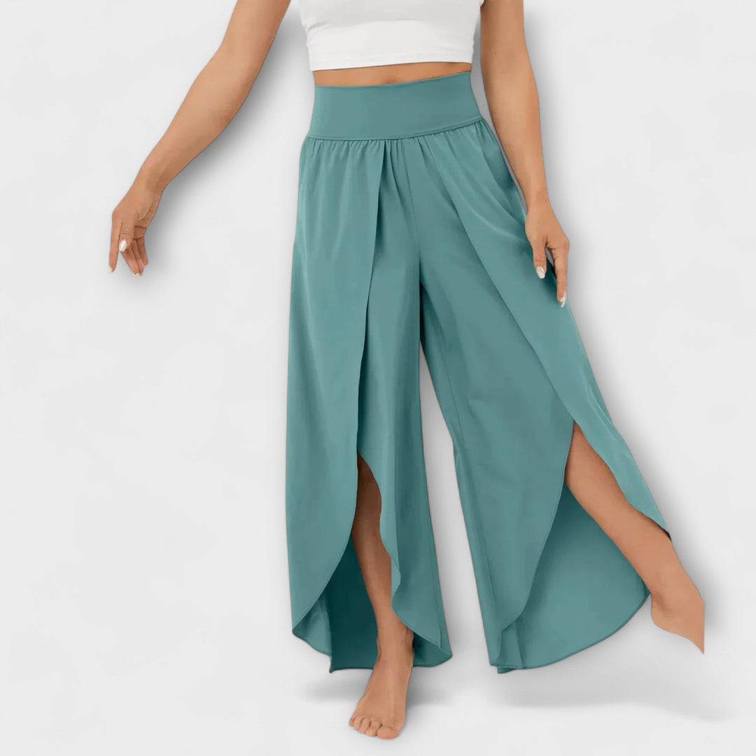 Frau trägt weite, türkisfarbene Haremshose mit hohem Bund und seitlichen Schlitzen. Modische Damenhose, ideal für Sommer und Freizeit.