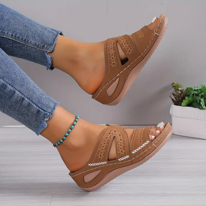 Braune Damen-Sandalen mit Keilabsatz, getragen mit blauen Jeans. Bequeme Sommerschuhe, ideal für Freizeit und Alltag.