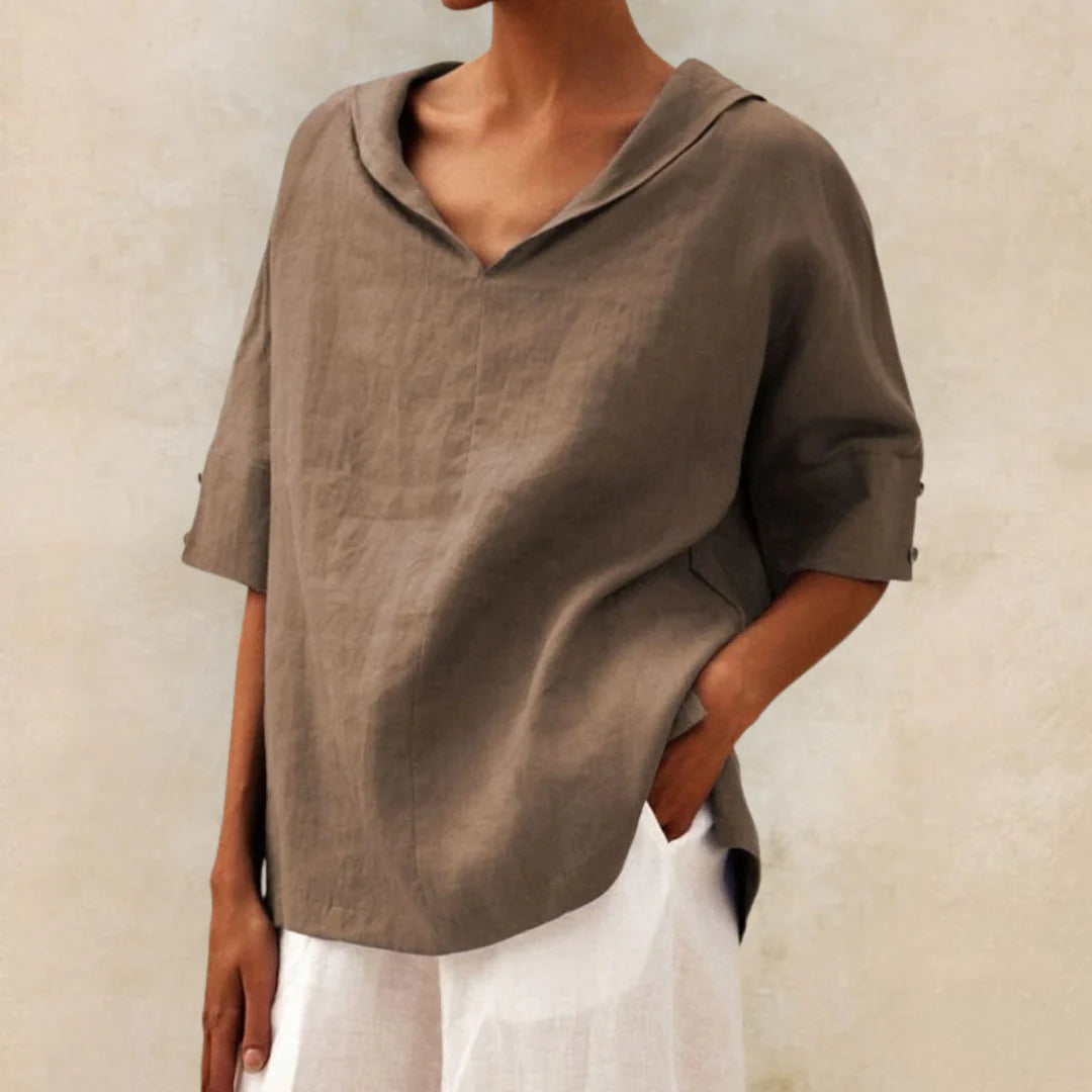 Damenmode: Lockeres, braunes Leinenhemd mit V-Ausschnitt und kurzen Ärmeln, kombiniert mit weißer Hose. Eleganter, minimalistischer Look.