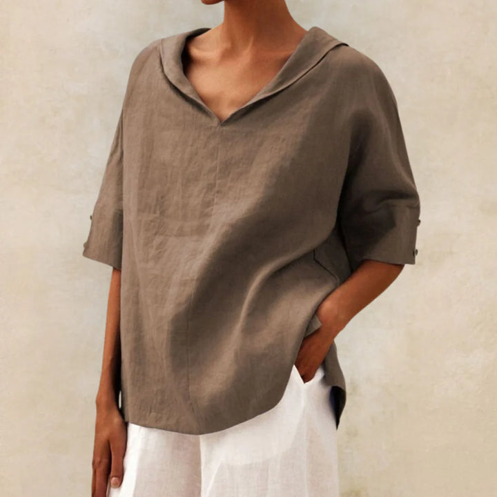 Damenmode: Lockeres, braunes Leinenhemd mit V-Ausschnitt und kurzen Ärmeln, kombiniert mit weißer Hose. Eleganter, minimalistischer Look.