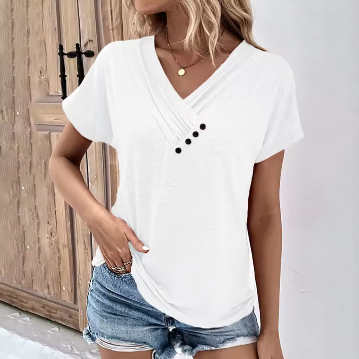 Weiße Damenbluse mit V-Ausschnitt und Knopfleiste, kombiniert mit blauen Jeansshorts. Sommermode, lässiger Stil, trendige Damenbekleidung.