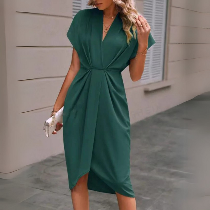 Grünes elegantes Damenkleid, knielang mit V-Ausschnitt, getragen von Frau auf städtischem Gehweg. Perfekt für Sommermode und Abendveranstaltungen.