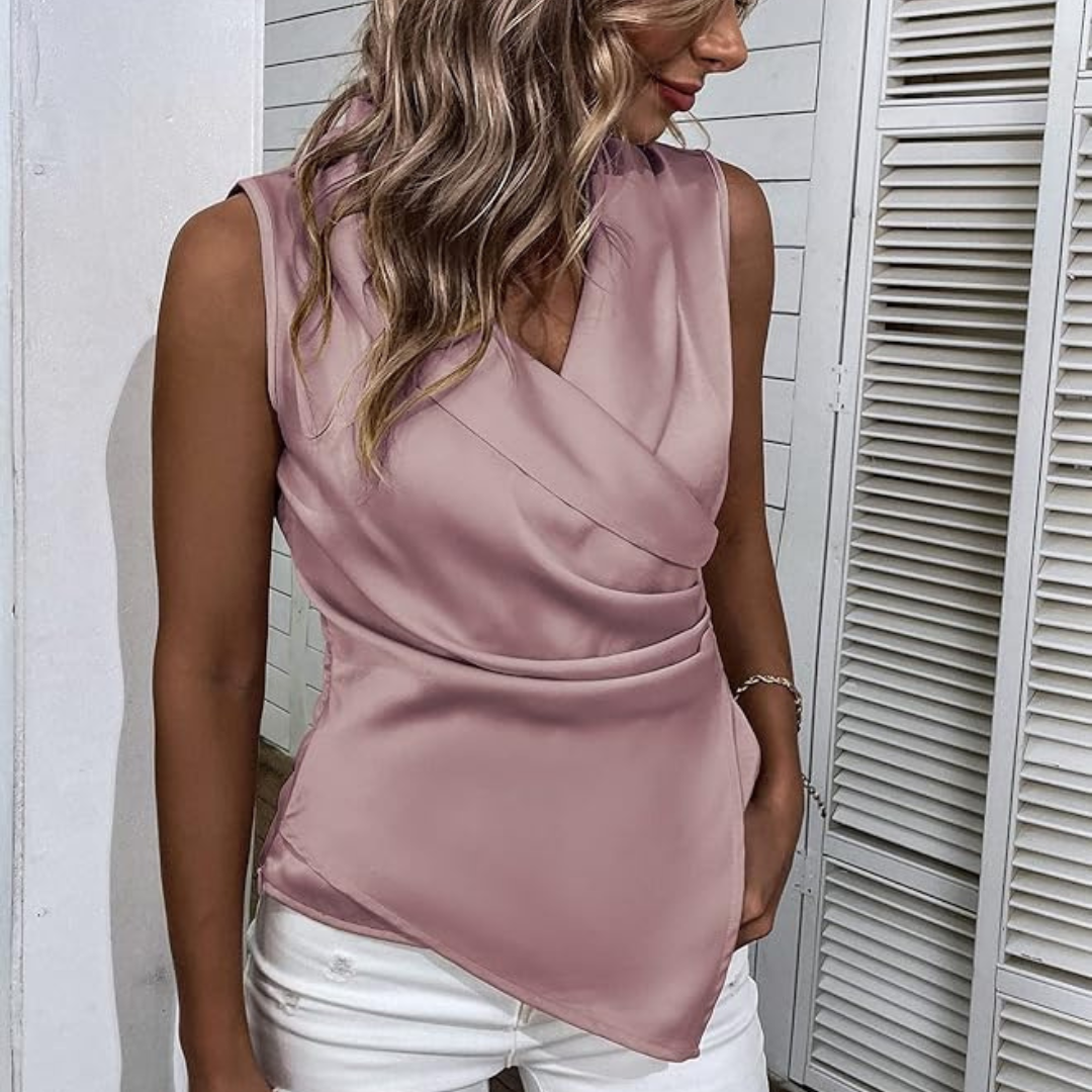 Frau in eleganter, ärmelloser, rosa Satinbluse mit V-Ausschnitt und weißer Hose. Modetrend, Damenmode, stilvolles Outfit, Sommerlook.