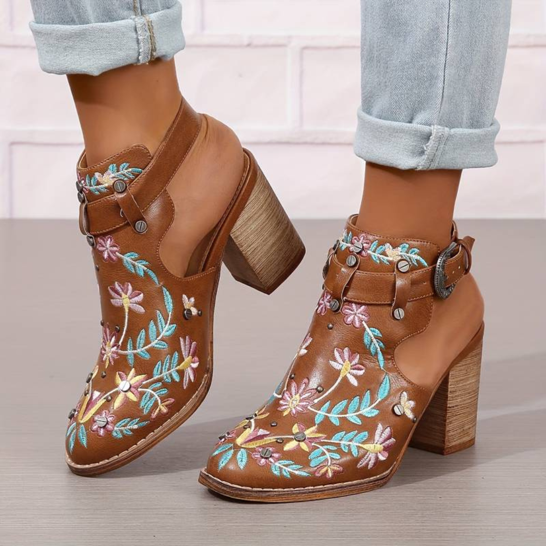 Braune Lederstiefeletten mit bunten Blumenstickereien, Blockabsatz und Schnallen, getragen mit hochgekrempelten Jeans. Modische Damenstiefel.