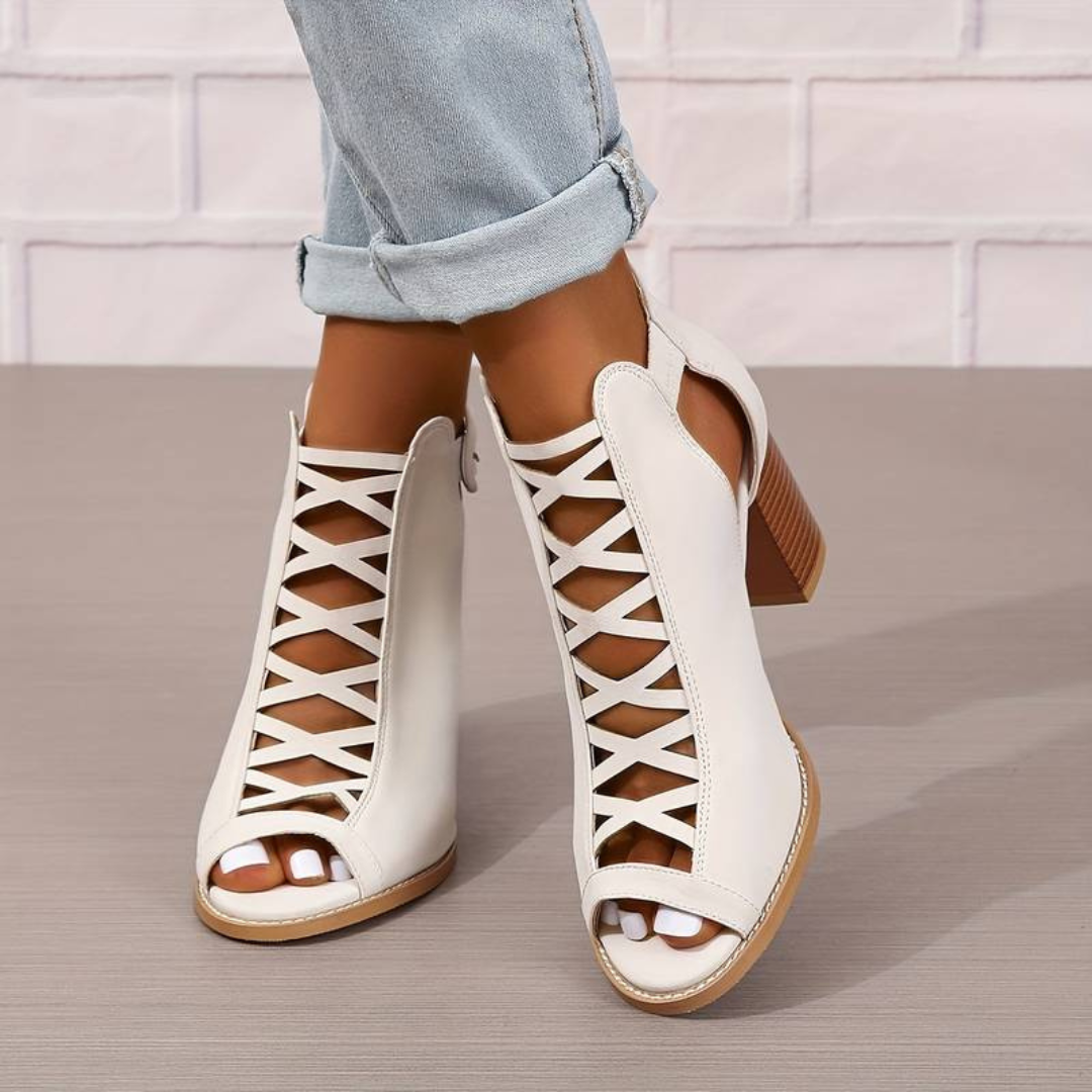 Weiße, offene Damenstiefeletten mit Blockabsatz und Schnürdesign, getragen zu hellblauen Jeans. Modische Sommerschuhe für Damen.