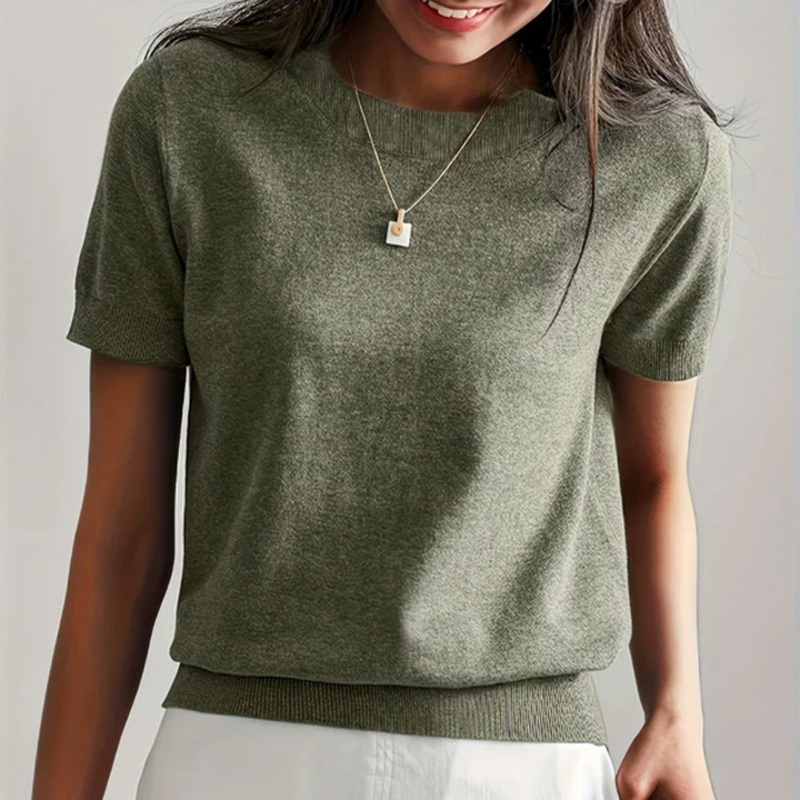 Dame trägt olivgrünen Strickpullover mit kurzen Ärmeln und Halskette. Modetrend, Damenbekleidung, eleganter Freizeitlook.