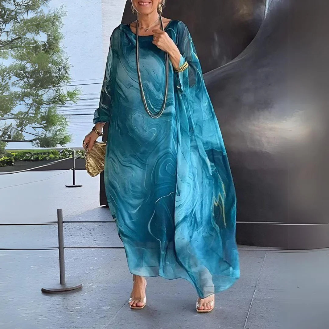 Elegante Frau in blauem, fließendem Kleid mit Marmormuster, goldener Clutch und Schmuck. Mode, Stil, Sommerkleid, Damenmode, elegantes Outfit.