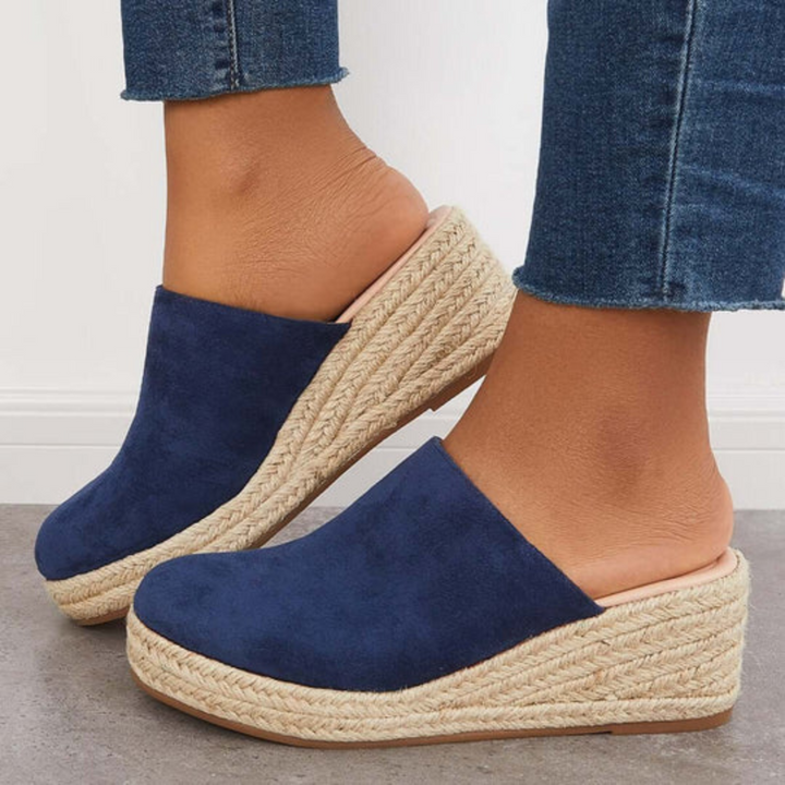 Damen-Wedges mit blauen Wildleder-Oberteilen und geflochtener Bastsohle, kombiniert mit blauen Jeans. Modische Sommerschuhe für Frauen.