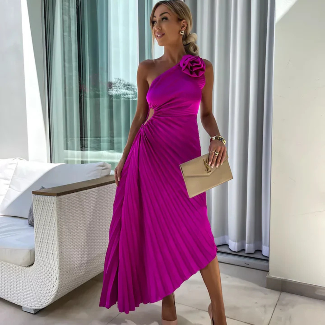 Elegantes, einseitiges, fuchsiafarbenes Kleid mit Blumenapplikation, getragen von Frau mit blonden Haaren, goldener Clutch, vor modernem Hintergrund.