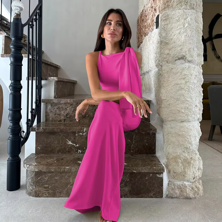 Frau in elegantem, pinkem Abendkleid sitzt auf Marmortreppe, moderne Inneneinrichtung, stilvolle Mode, luxuriöses Design, zeitgenössischer Stil.