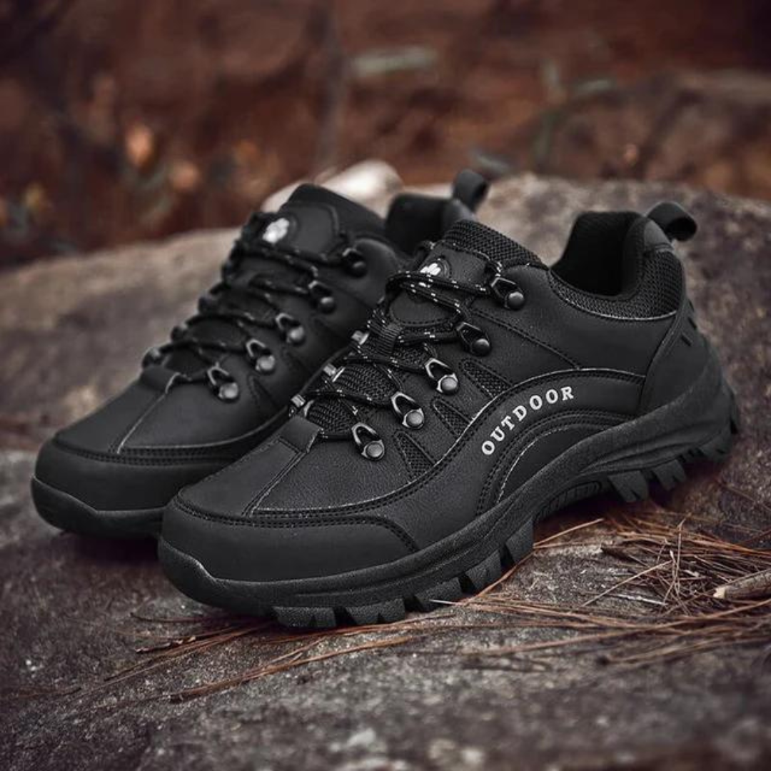Schwarze Outdoor-Wanderschuhe auf Felsen, robustes Design, rutschfeste Sohle, ideal für Trekking und Bergsteigen. Hochwertige Outdoor-Schuhe.