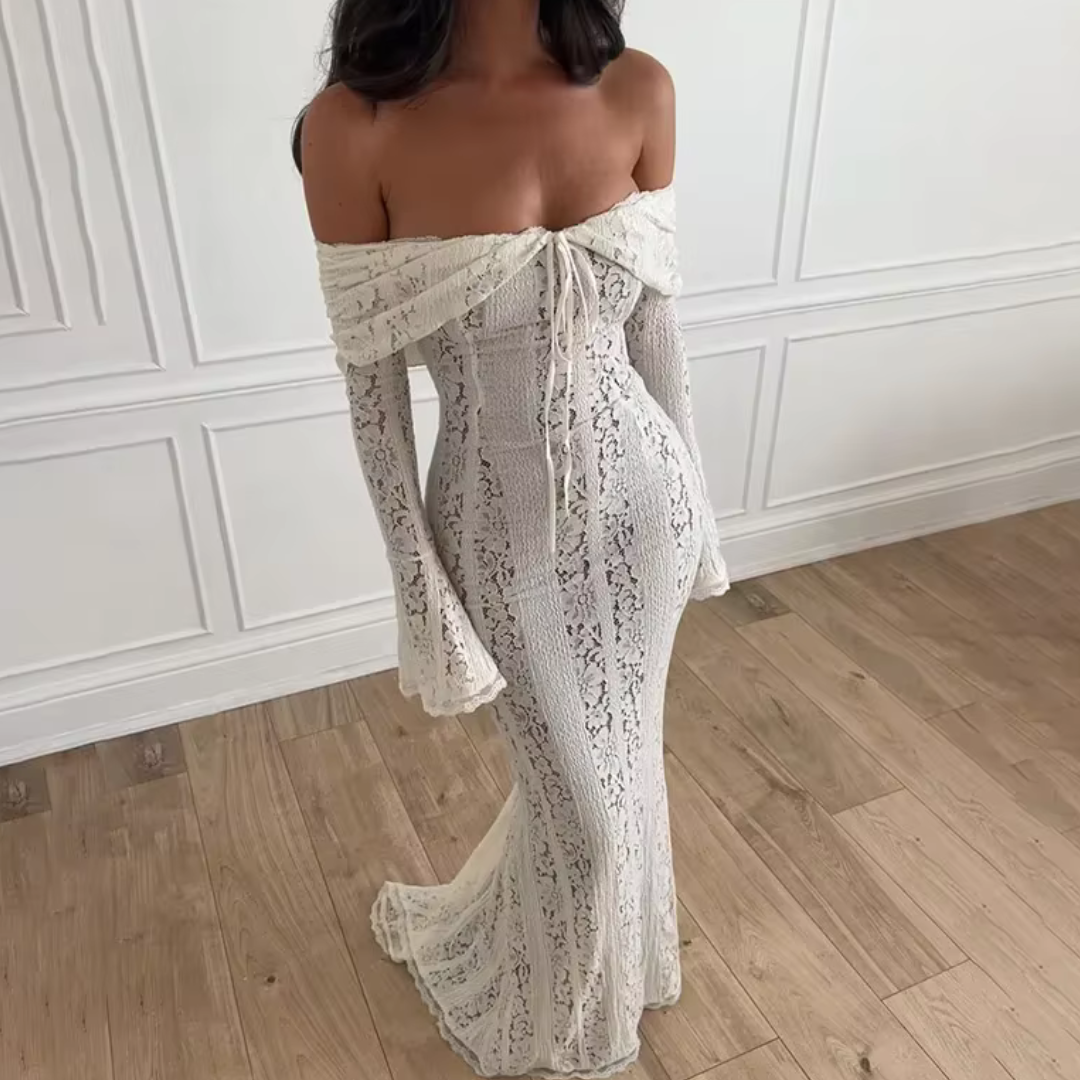 Schulterfreies Spitzenkleid in Weiß, figurbetont, mit langen Ärmeln und Schnürung, auf Holzboden vor weißer Wand. Elegantes Abendmode-Design.