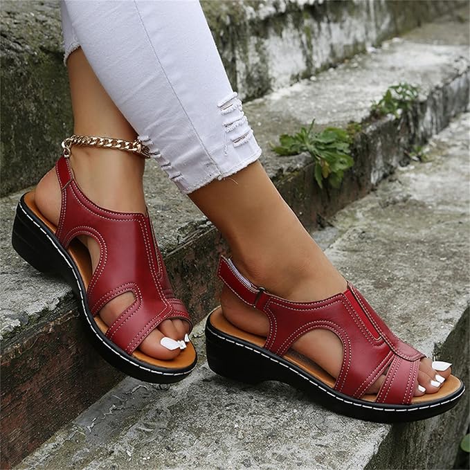 Rote Sandalen mit Keilabsatz, getragen von einer Person in weißen, zerrissenen Jeans auf einer Treppe. Modische Sommerschuhe, bequem und stilvoll.