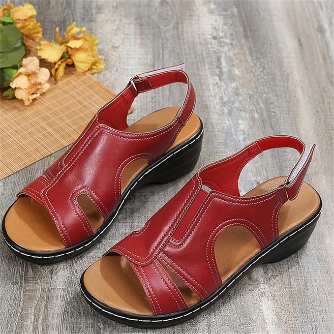 Rote Damensandalen aus Leder mit Keilabsatz auf Holzboden, dekoriert mit gelben Blumen. Bequeme Sommerschuhe, ideal für Freizeit und Alltag.