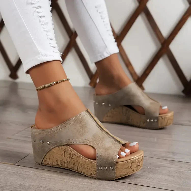 Damen Sandalen mit Keilabsatz, beige, aus Wildlederimitat, mit Nieten, getragen mit weißen Jeans. Modische Sommerschuhe für Frauen.