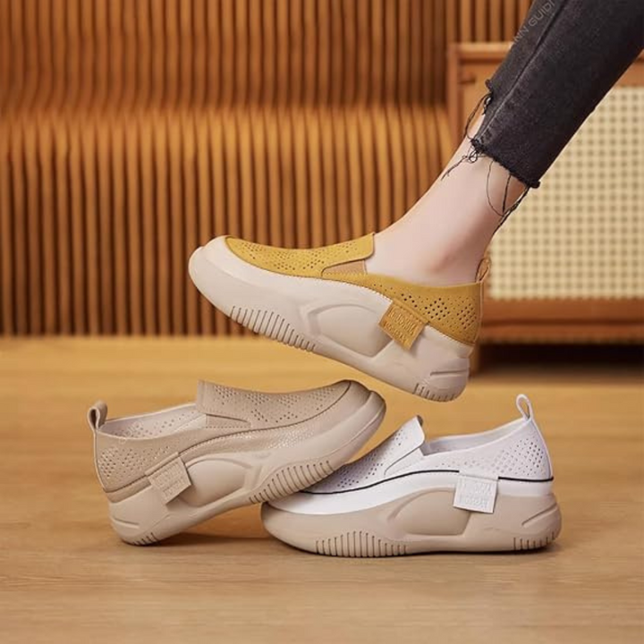 Damen-Sneaker in Gelb, Beige und Weiß auf Holzboden. Modische, bequeme Slip-On-Schuhe mit perforiertem Design. Ideal für Freizeit und Alltag.