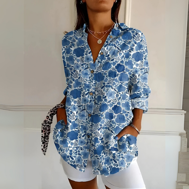 Frau trägt blau-weiß geblümte Bluse, weiße Shorts, Halsketten; modisches Sommeroutfit, lässiger Stil, florales Design, Damenmode.