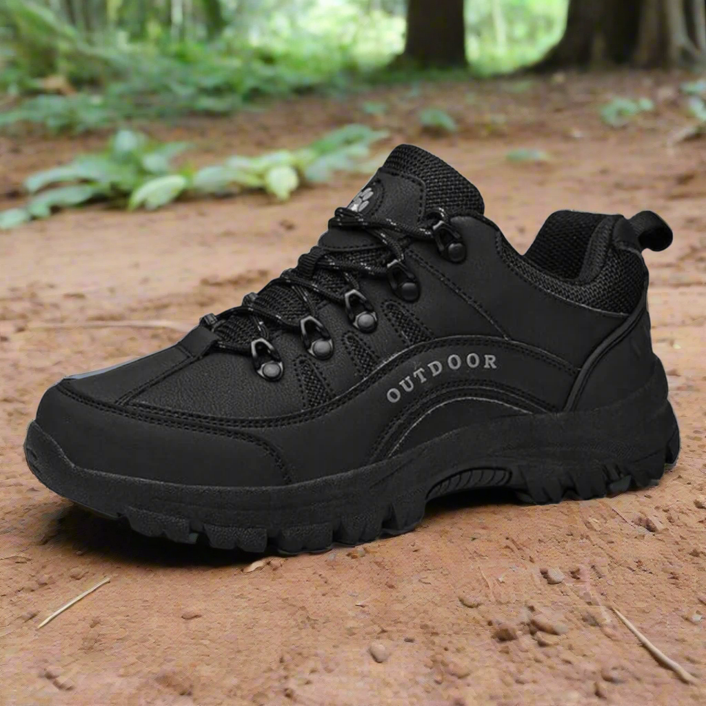 Schwarzer Outdoor-Wanderschuh auf Waldboden, robustes Design, rutschfeste Sohle, ideal für Trekking und Naturabenteuer.